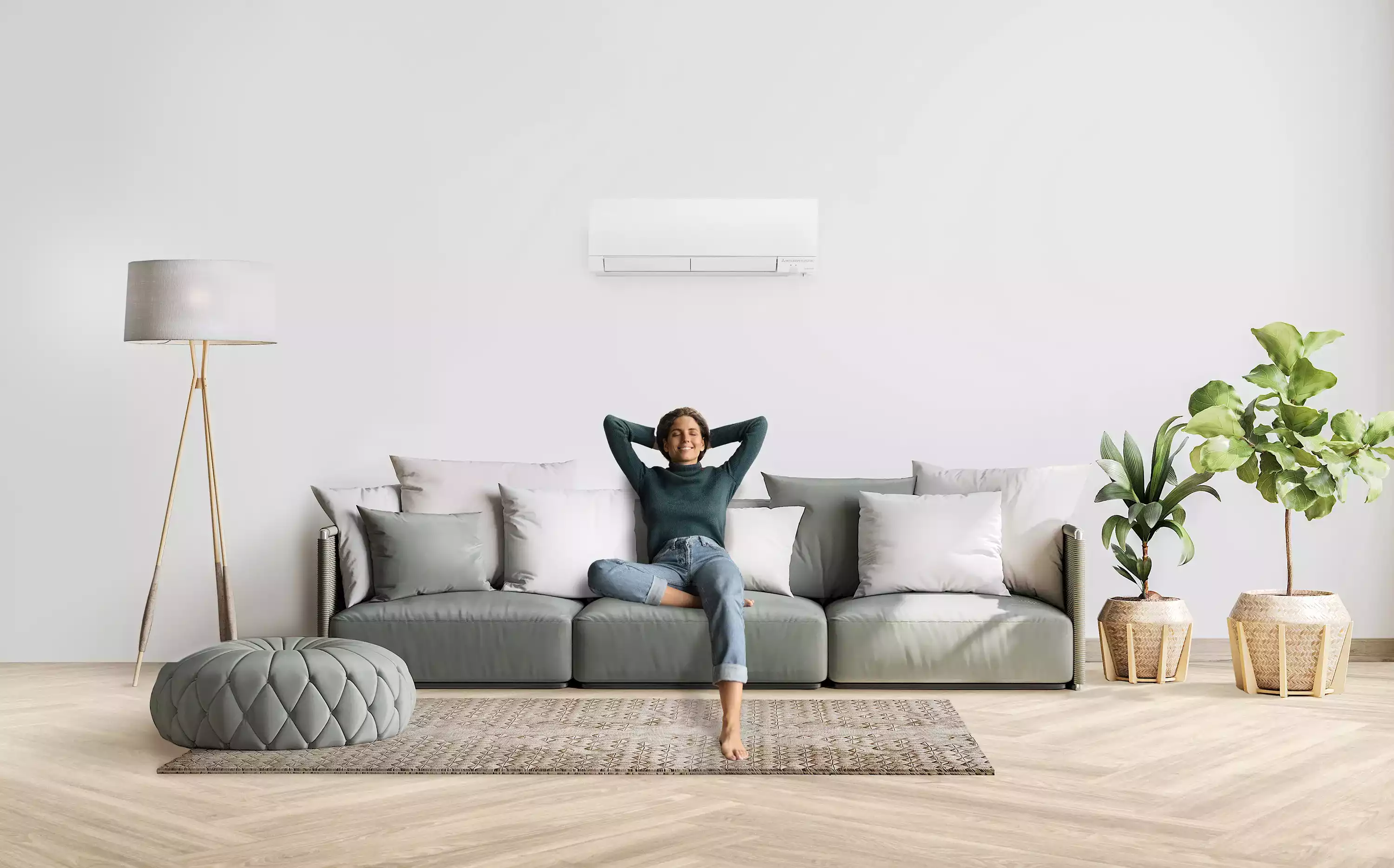 Woman sitting on a sofa with arms behind her head, relaxing in a bright living room with plants.