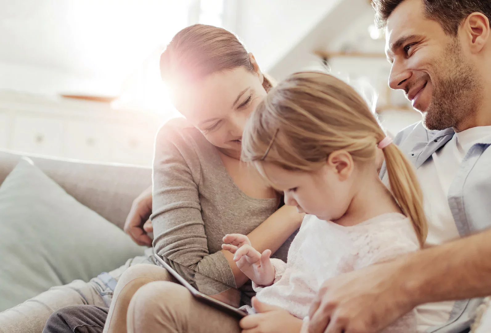 A family relaxing in their living room while their children play on the floor, enjoying time together.