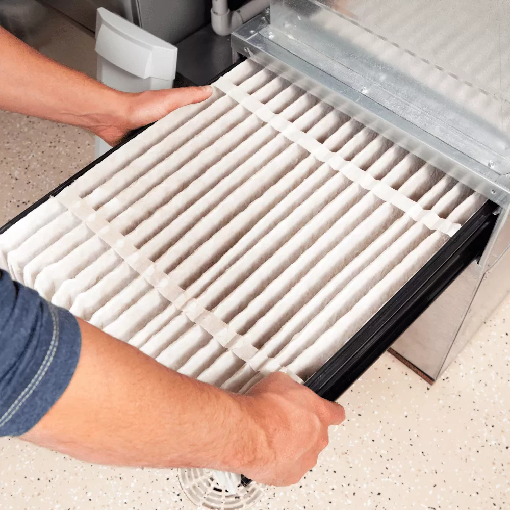 A person replacing a clean HVAC filter in an air handling unit.
